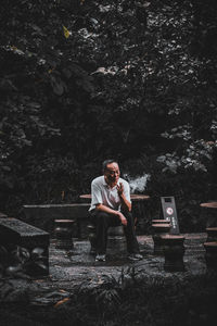 Full length of young man sitting on mobile phone