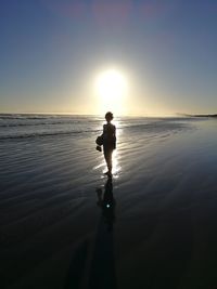 Silhouette man on beach against sky during sunset