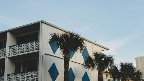 Low angle view of palm tree and building against sky