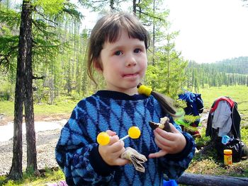 Portrait of cute baby girl holding fruit on tree