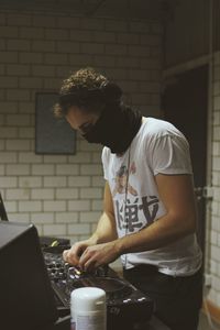 Young man wearing mask playing music at studio