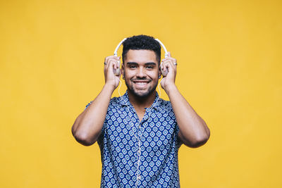 Portrait of smiling young man against yellow background