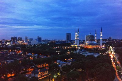 Illuminated cityscape against cloudy sky