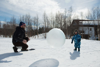 Father and son playing with ball in snow in winter on sunny day