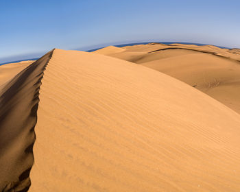 Sand dunes in desert against clear sky