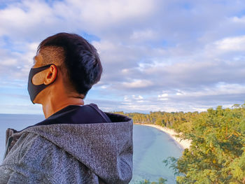 Rear view of man looking at sea against sky