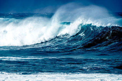 Scenic view of waves splashing in sea against sky