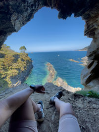 Low section of person on beach against sky