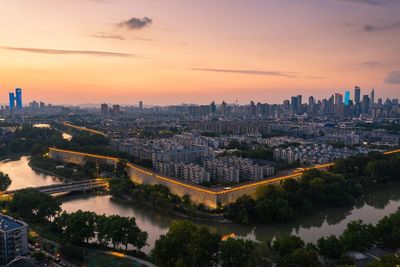 High angle view of river and buildings against sky during sunset