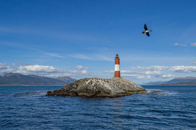 Lighthouse by sea against sky