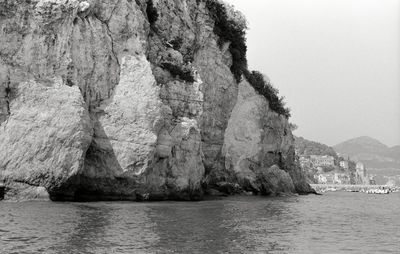 Rock formations by sea against clear sky