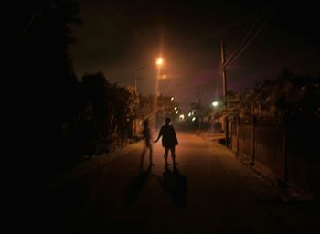 People walking on illuminated road in city at night