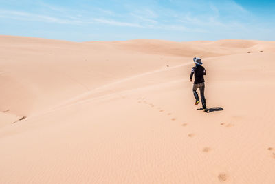 Full length of man on sand dune in desert against sky