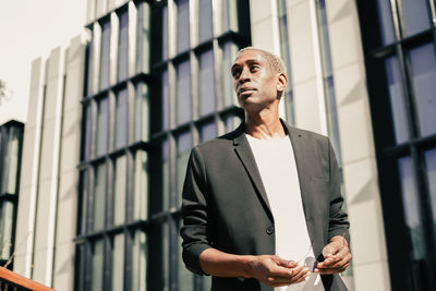 Young man looking away against building
