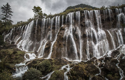 Low angle view of waterfall against rocks