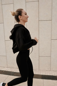 Side view of woman running against wall