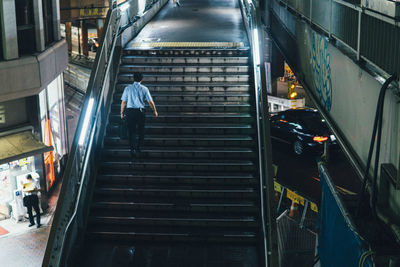 Rear view of man walking on escalator