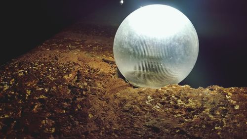 Close-up of illuminated ball on rock at night