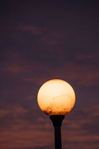 Low angle view of illuminated lamp against sky during sunset