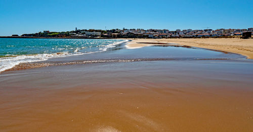 Scenic view of beach against clear blue sky