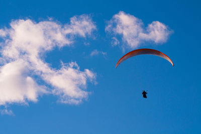 Low angle view of person paragliding against blue sky