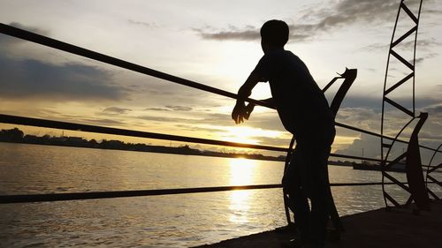 Silhouette man standing by sea against sky during sunset