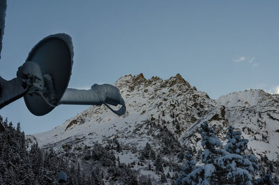 Low angle view of snow covered satellite dish against mountain