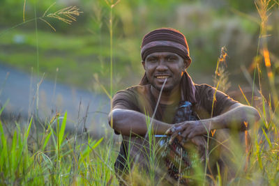 Portrait of young man sitting on field