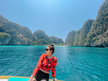 Woman in sea against mountains