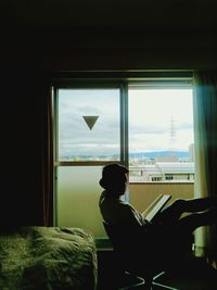 Rear view of woman looking through window