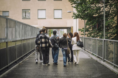 Rear view of male and female friends walking together on footpath