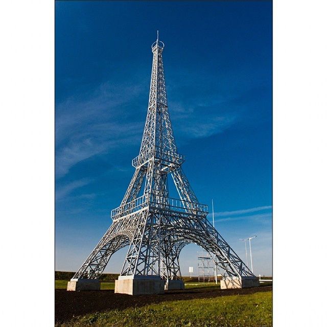 transfer print, built structure, sky, architecture, low angle view, metal, auto post production filter, tower, metallic, tall - high, blue, eiffel tower, day, building exterior, outdoors, travel destinations, no people, clear sky, famous place, cloud