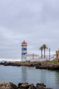 Lighthouse by sea against clear sky