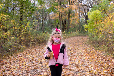 Portrait of girl standing against trees during autumn