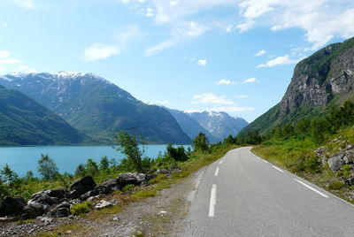 Road leading towards mountains against sky