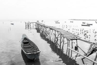 Boat moored on pier by sea against clear sky