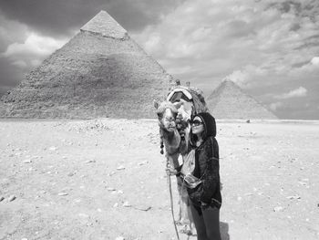 View of person looking at pyramids with an asian girl/woman and a camel in cairo. 