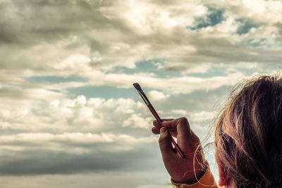 Portrait of woman holding cigarette against sky