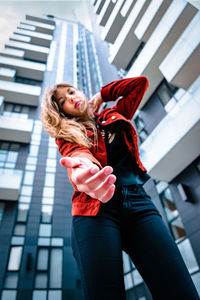 Young woman with red umbrella standing against built structure