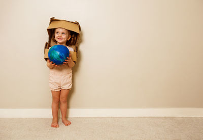 Portrait of cute girl standing against wall