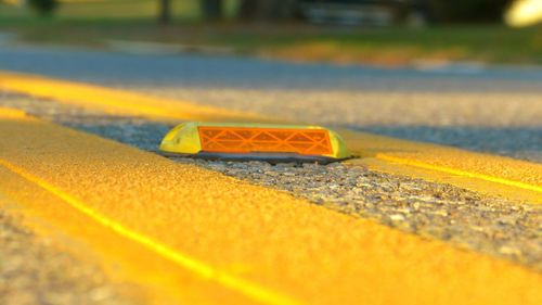 Close-up of yellow car on road