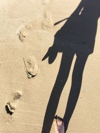 Low section of people standing on sand at beach