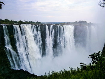 Scenic view of waterfall against sky