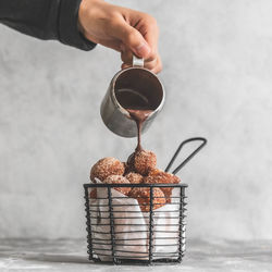 Chocolate being poured over donut holes churros on table against wall