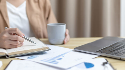 Midsection of woman using laptop on table