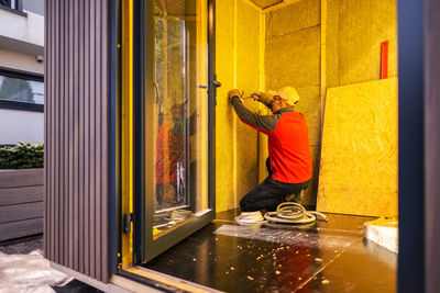 Side view of man photographing through window