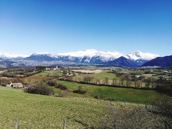 Scenic view of field and mountains against clear blue sky