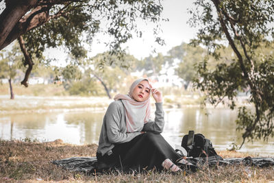 Portrait of young woman sitting at lakeshore