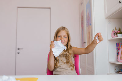 Happy schoolgirl tears up a sheet of a school notebook because of an incorrectly completed homework