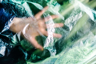 Cropped hand of person seen through plastic